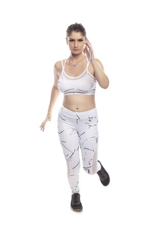 Woman wearing sports clothing running and isolated on white background for composites.  She is an active and fit Caucasian female who looks like she is exercising or practicingの写真素材