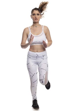 Woman wearing sports clothing running and isolated on white background for composites.  She is an active and fit Caucasian female who looks like she is exercising or practicingの写真素材