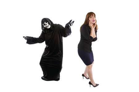 Scared businesswoman paranoid of catching a deadly disease represented by the grim reaper.  She is frightened of contracting a pandemic illness such as coronavirusの写真素材