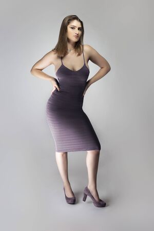 Female fashion model wearing a trendy slim fit purple, or lavender violet summer dress in a studio for summer and spring collection catalog. She is sexy and looking confidentの写真素材