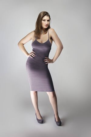 Female fashion model wearing a trendy slim fit purple, or lavender violet summer dress in a studio for summer and spring collection catalog. She is sexy and looking confidentの写真素材