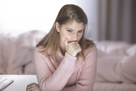 Lonely woman at home during a pandemic lockdown or quarantine feeling despair and sadness because of unemployment and furlough.  She is isolated and stuck in the apartment and is stressful for mental healthの写真素材