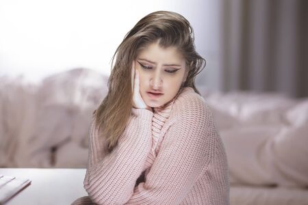 Lonely woman at home during a pandemic lockdown or quarantine feeling despair and sadness because of unemployment and furlough.  She is isolated and stuck in the apartment and is stressful for mental healthの写真素材