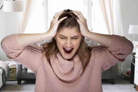 Woman getting impatient and angry for having to stay at home during pandemic lock down or quarantine.  She is upset and having a mental breakdown because of boredom or stressの写真素材