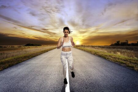 Fit woman wearing sportswear running or jogging alone on an isolated road for exercise during social...