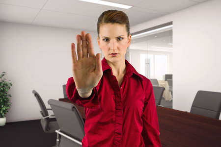 Businesswoman holding hands up as a stop gesture to tell co-workers to stay away and keep social...