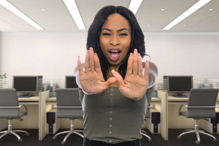 Businesswoman holding hands up as a stop gesture to tell co-workers to stay away and keep social distancing in the office or workplace because she is scaredの写真素材