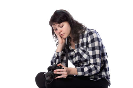 Young female freelance professional photographer or art student or photojournalist on a white background holding a camera. Looking depressed and lack of self confidenceの写真素材