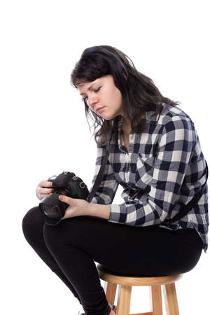 Young female freelance professional photographer or art student or photojournalist on a white background holding a camera. Looking depressed and lack of self confidenceの写真素材