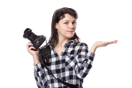 Young female freelance professional photographer or art student or photojournalist on a white background holding a camera. She is presenting or advertising somethingの写真素材