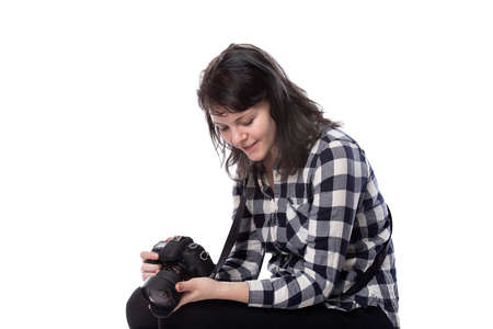 Young female freelance professional photographer or art student or photojournalist on a white background holding a camera. Looking depressed and lack of self confidenceの写真素材
