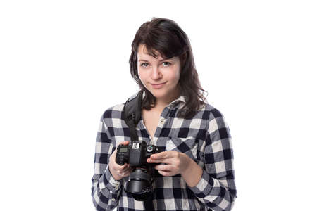 Young female freelance professional photographer or art student or photojournalist on a white background holding a camera.  She looks like she is thinking creativelyの写真素材