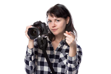 Young female freelance professional photographer or art student or photojournalist on a white background holding a camera. She is pointing forward at her clientの写真素材