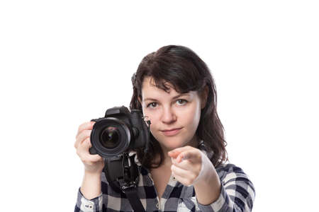 Young female freelance professional photographer or art student or photojournalist on a white background holding a camera. She is pointing forward at her clientの写真素材