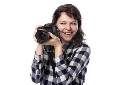 Young female freelance professional photographer or art student or photojournalist on a white background holding a camera. She looks happy and successfulの写真素材