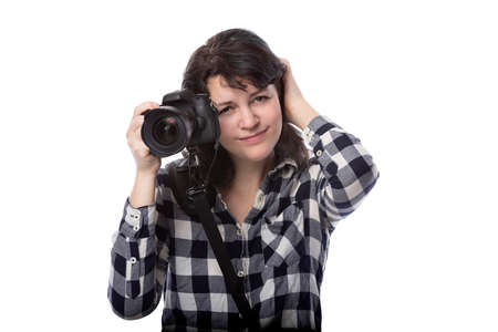 Young female freelance professional photographer or art student or photojournalist on a white background holding a camera. She is confused or shyの写真素材