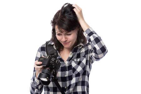 Young female freelance professional photographer or art student or photojournalist on a white background holding a camera with thumbs downの写真素材