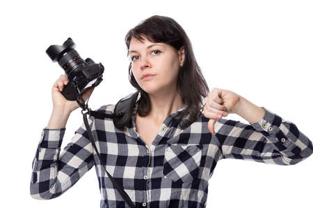 Young female freelance professional photographer or art student or photojournalist on a white background holding a camera with thumbs downの写真素材