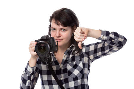 Young female freelance professional photographer or art student or photojournalist on a white background holding a camera with thumbs downの写真素材