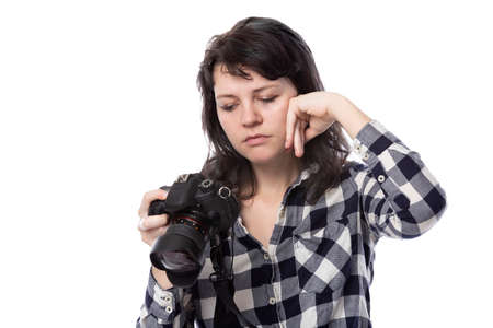 Young female freelance professional photographer or art student or photojournalist on a white background holding a camera. She is feeling sick or unwellの写真素材