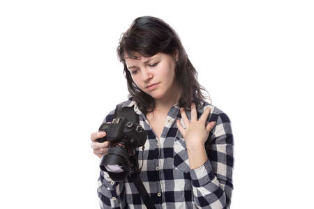 Young female freelance professional photographer or art student or photojournalist on a white background holding a camera. She looks worried of mistakesの写真素材