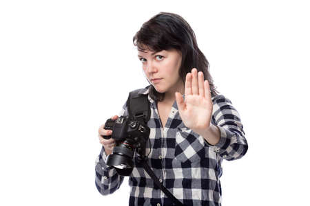 Young female freelance professional photographer or art student or photojournalist on a white background holding a camera telling client to stopの写真素材