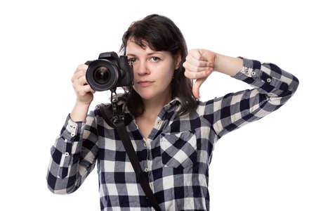 Young female freelance professional photographer or art student or photojournalist on a white background holding a camera with thumbs downの写真素材
