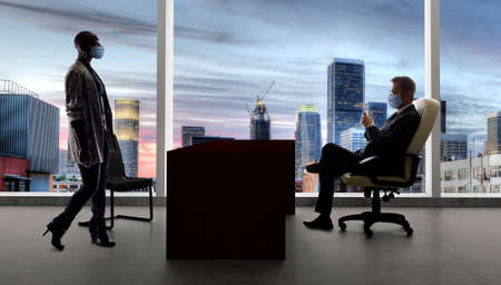 Businessman and businesswoman working in the office during a pandemic and keeping social distance and wearing protective face masks to prevent viral infection of covidの写真素材
