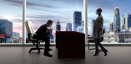 Businessman and businesswoman working in the office during a pandemic and keeping social distance and wearing protective face masks to prevent viral infection of covidの写真素材