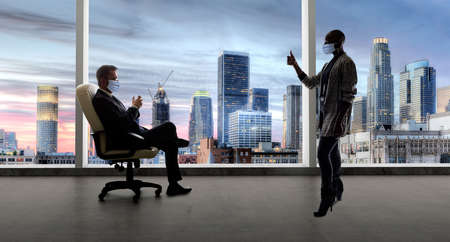 Businessman and businesswoman working in the office during a pandemic and keeping social distance and wearing protective face masks to prevent viral infection of covidの写真素材