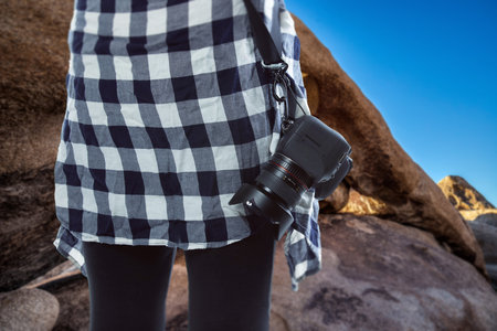 Professional photographer or hobbyist traveling through a desert landscape and holding a camera. ...