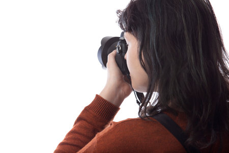 Side view of a female photographer holding a camera isolated on a white background for composites.  The model is posed to face a scenery or copy spaceの写真素材