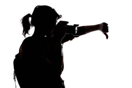Silhouette of a photographer with a camera on a white background isolated for composites. She is posed with a thumbs down gestureの写真素材