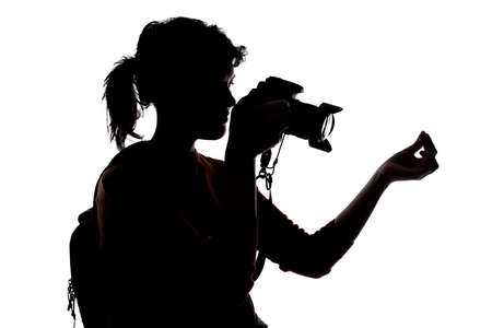 Silhouette of a photographer with a camera on a white background isolated for composites. She is signaling with money gesture to collect payの写真素材