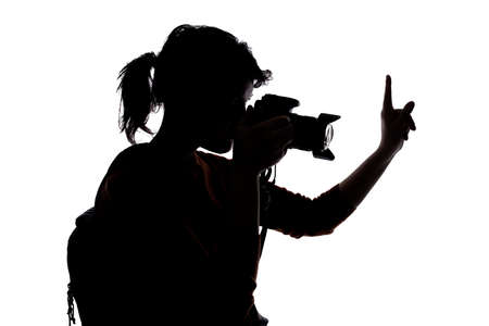 Silhouette of a photographer with a camera on a white background isolated for composites. She is posed as if telling model to stop or pauseの写真素材