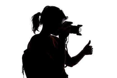 Silhouette of a photographer with a camera on a white background isolated for composites. She is posed with a thumbs up gestureの写真素材