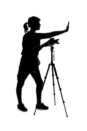 Silhouette of a photographer with a camera on a white background isolated for composites.  She is posed with a stop gestureの写真素材