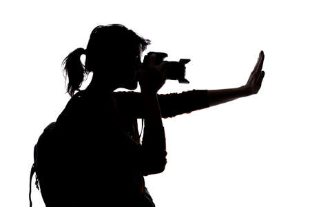 Silhouette of a photographer with a camera on a white background isolated for composites.  She is posed with a stop gestureの写真素材