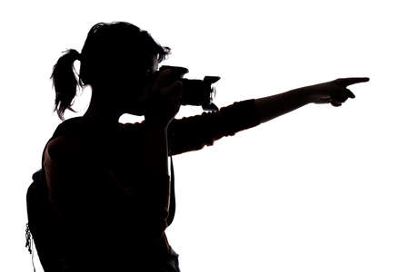 Silhouette of a photographer with a camera on a white background isolated for composites. She is pointing forwardの写真素材