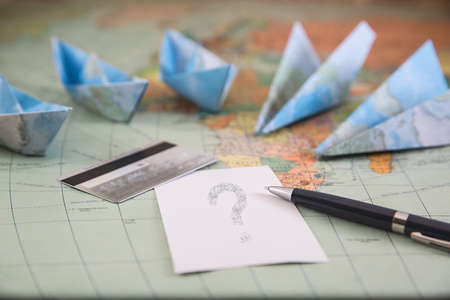 Traveling concept. Paper boats and paper airplanes, plastic card, paper and pen on a mapの写真素材