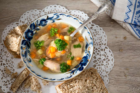 Chicken soup with vegetables on a wooden table with a napkin. Spoon in the bowl of soup.の写真素材