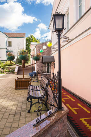 The courtyard with a lantern, bench with forged elements, flowers in potsの写真素材