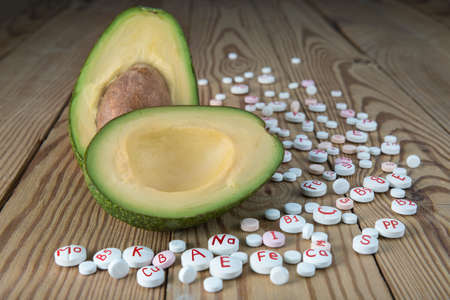 Avocado and synthetic vitamins on a wooden table. The concept of healthy food and natural vitamins....