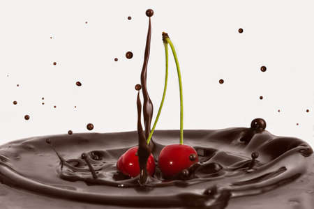 Two red cherries. A splash of chocolate from the fall of cherries. Delicious dessert