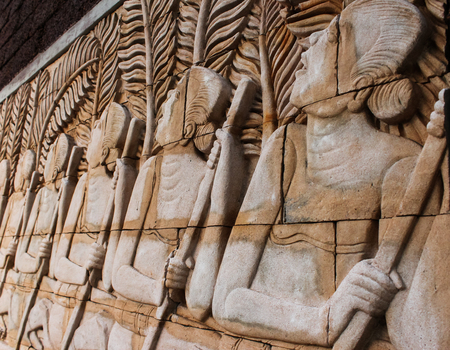 people sculpture on the brown sandstone wall in thailandの写真素材