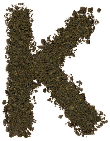 Alphabet made of brown soil on white background. High sharp and detail. Letter Kの写真素材