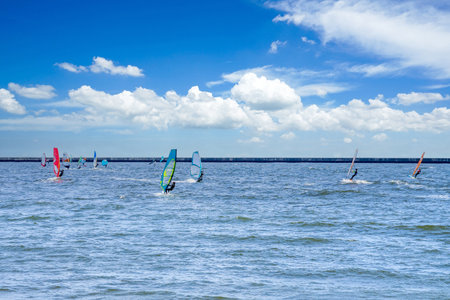 Windsurfer surfing on the wind under a sky full of summer cloudsの写真素材