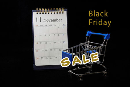 Black Friday Sale Concept with Shopping Cart and Calendar on a Black Backgroundの写真素材