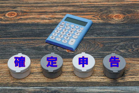 A calculator and the words "Tax Filing" placed on a wooden boardの写真素材