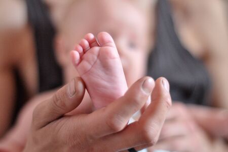 Baby feet in father hands. Tiny Newborn Baby's feet on male hands closeup. Dad and his child. Happy...